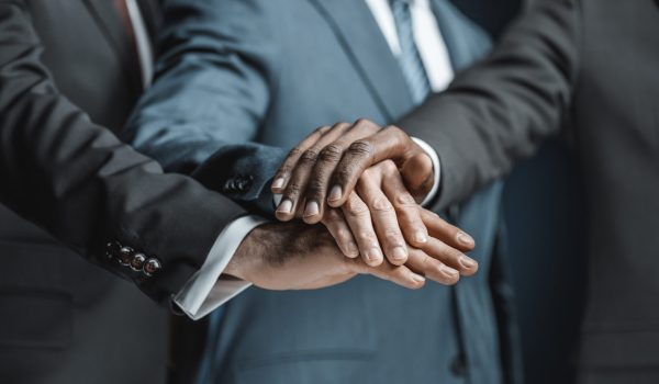 cropped shot of multiethnic group of businessmen holding hands together